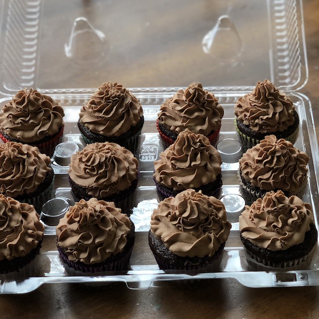 One dozen chocolate cupcakes with chocolate buttercream icing.